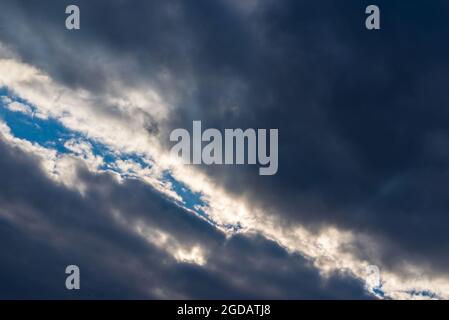 Lichtstrahlen, die durch dunkle Wolken leuchten.schöner dramatischer Himmel mit Sonnenstrahlen.dramatischer Himmel mit Sonnenstrahlen. Stockfoto