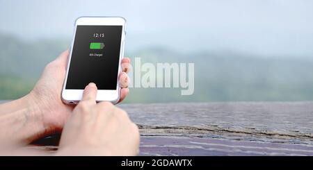 Weibliche Hand hält Handy mit aufgeladenem Akku auf dem Bildschirm Stockfoto