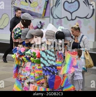 Manchester, Großbritannien, 12. August 2021. Tägliches Leben auf den Straßen des Stadtzentrums von Manchester, Großbritannien. Ein kleines Kind und eine Frau schauen sich einen Trolley an, der Mützen und Spielzeug im Stadtzentrum von Manchester, England, Vereinigtes Königreich, Credit: Terry Waller/Alamy Live News Stockfoto