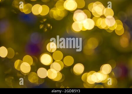 Verschwommenes weihnachtslicht abstrakter Hintergrund vor dunkler Kulisse. Kreisförmige Reflexionen von Weihnachtslichtern Stockfoto