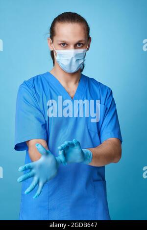 Junger Mann Arzt in Uniform trägt Handschuhe Stockfoto