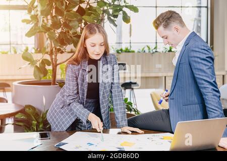 Berufstätige Frauen treffen sich mit einem Geschäftsmann, der gemeinsam Arbeitsplätze in einem grünen, modernen Büro plant. Stockfoto