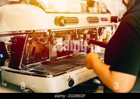 Barista arbeitet in einem Café mit italienischen Espressomaschine machen einen Kaffee Bild vintage Ton. Stockfoto