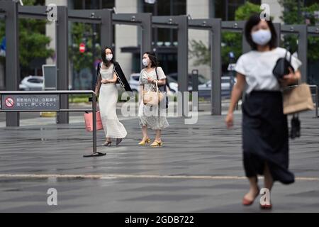 Tokio, Japan. August 2021. Elegant gekleidete Frauen gehen über einen Platz und tragen Gesichtsmasken und Masken. â Credit: dpa/Alamy Live News Stockfoto