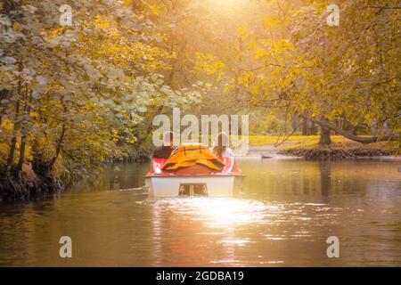 Verliebtes Paar in einem Katamaran, Wasserfahrrad in einem Park im Herbst, Sonnenuntergang Stockfoto