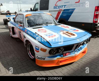 Drei Viertel Vorderansicht eines blau, weiß und orange BMW 3.0L CSL im International Paddock, während der Silverstone Classic 2021 Stockfoto