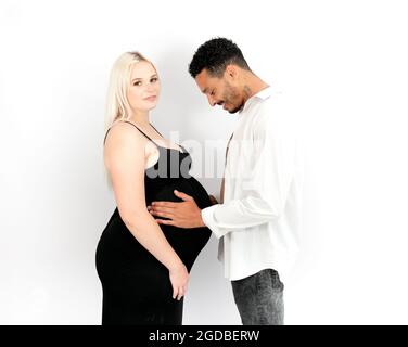 Profilansicht eines stilvollen und glücklichen multiethnischen Paares, das ein Baby erwartet Stockfoto