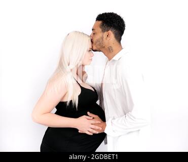 Profilansicht eines stilvollen und glücklichen multiethnischen Paares, das ein Baby erwartet Stockfoto