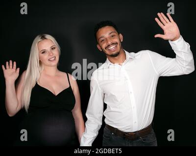 Porträt eines stilvollen, stolzen und glücklichen multiethnischen Paares, das ein Baby erwartet und freudig verzichtet Stockfoto