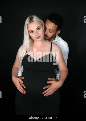 Der zukünftige Vater mit gemischter Rasse hält den Bauch seiner schwanger werdenden kaukasischen Frau Stockfoto