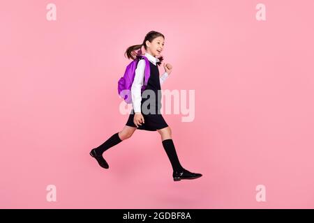 In voller Länge Körpergröße Foto Schülerin springen halten Rucksack zu Fuß zur Schule isoliert pastellrosa Farbe Hintergrund Stockfoto