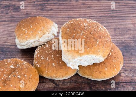 Fünf frisch gebackene Weizenbrötchen auf einem alten Eichentisch Stockfoto