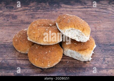 Sechs frisch gebackene Weizenbrötchen auf einem alten Eichentisch Stockfoto