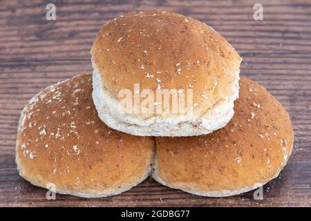 Drei frisch gebackene Weizenbrötchen auf einem alten Eichentisch Stockfoto