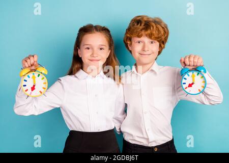 Porträt von zwei attraktiven fröhlichen Kindern mit kindlicher Uhr umarmenden Glocke Ring isoliert über hellen blauen Hintergrund Stockfoto