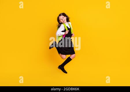In voller Länge Körpergröße Foto Schülerin springen trägt Rucksack isoliert lebendige gelbe Farbe Hintergrund Stockfoto