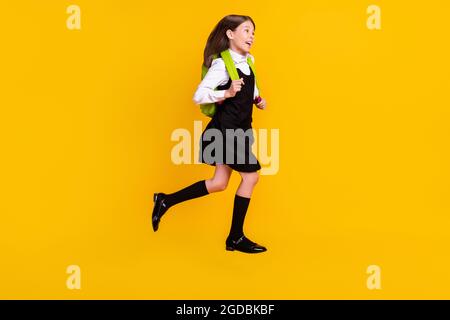 In voller Länge Körpergröße Foto Schülerin springen gehen zur Schule mit Rucksack isoliert lebendige gelbe Farbe Hintergrund Stockfoto