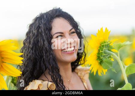 Porträt einer schönen lächelnden dunkelhaarigen Frau mit einer großen Sonnenblume in den Händen Stockfoto