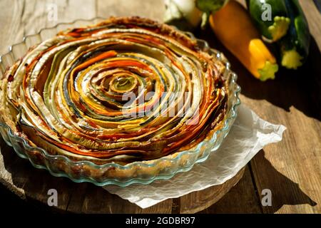 Gemüsekuchen mexikanische Sonne. Runde, offene Torte aus Zucchini, Auberginen und Karotten. Nahaufnahme von oben. Gesunde pflanzliche Lebensmittel. Vegetarismus. Spirale Stockfoto