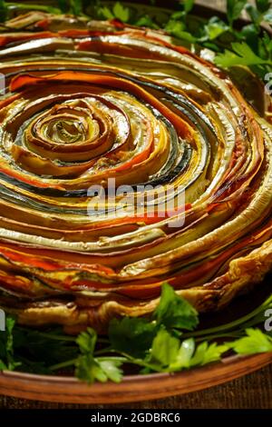 Gemüsekuchen mexikanische Sonne. Runde, offene Torte aus Zucchini, Auberginen und Karotten. Nahaufnahme von oben. Gesunde pflanzliche Lebensmittel. Vegetarismus. Spirale Stockfoto