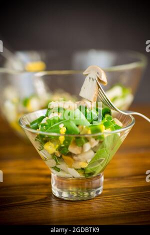 Frische Frühlingsdiät Salat von Pilzen, Eiern, grünen Zwiebeln auf einem Holztisch Stockfoto
