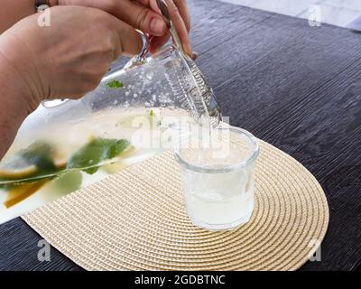 Im Straßencafé wird hausgemachte Limonade aus einem Glaskrug in Glas gegossen Stockfoto