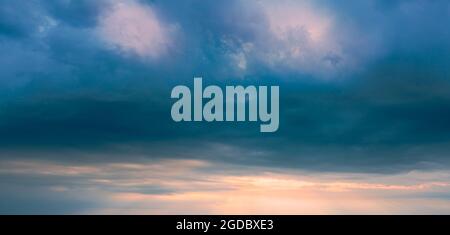 Panorama des stürmischen Himmels vor Sonnenuntergang. Dunkle Wolken am Sonnenuntergangshimmel. Stockfoto