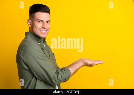 Foto Porträt Mann lächelnd halten Copyspace auf den Händen isoliert lebendige gelbe Farbe Hintergrund Stockfoto