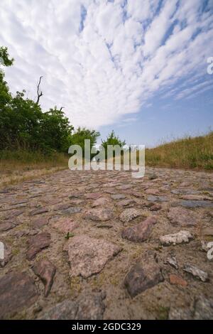 Sehr alter Kopfsteinpflasterweg in idyllischer Landschaft Stockfoto