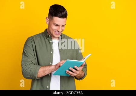 Portrait von attraktiven fröhlich smart clever fokussierten Kerl lesen interessante Buch isoliert über hellen gelben Hintergrund Stockfoto