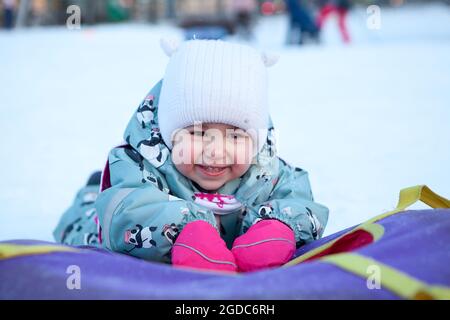 Lächelndes und lachendes Baby mit Schneelöhrchen, Porträt. Kaukasisches Kind Stockfoto