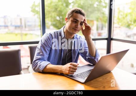 Weiß nicht. Portrait of Traurigkeit müde bärtige junge Freiberufler sitzen allein im Café und auf der Suche nach einer Arbeit auf dem Laptop sind in schlechter Stimmung ohne goo Stockfoto