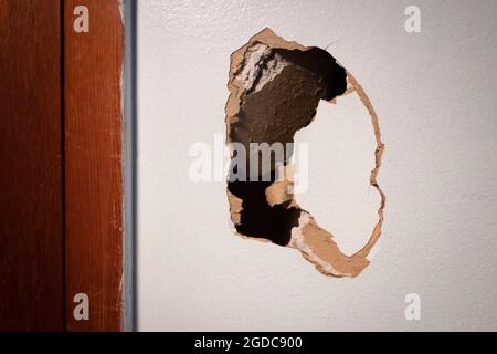 Großes Loch in beschädigter Trockenbauwand, reparaturbedürftig Stockfoto