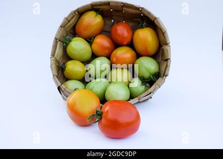 Drei verschiedene Arten von Tomaten. Grüne, gelbe, rote Tomaten in einem Korb auf weißem Hintergrund Stockfoto