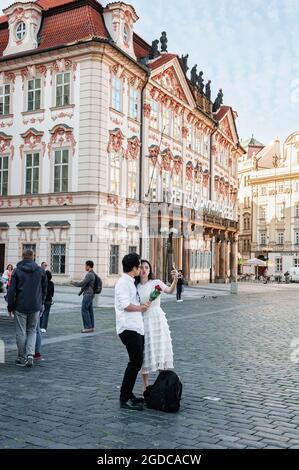 13. August 2017 Prag, Tschechische Republik. Asiatische Touristen werden vor dem Hintergrund der Sehenswürdigkeiten der Stadt fotografiert. Liebhaber macht ein Selfie dagegen Stockfoto