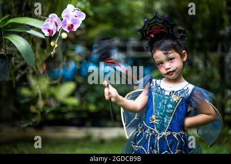 Süßes asiatisches weibliches Kind posiert in einem lustigen Hexen Halloween Kostüm Stockfoto