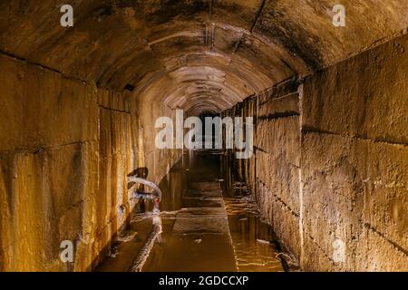 Alter dunkler gewölbter unterirdischer, überfluteter Kanaltunnel. Stockfoto