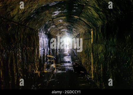 Alter dunkler gewölbter unterirdischer, überfluteter Kanaltunnel. Stockfoto