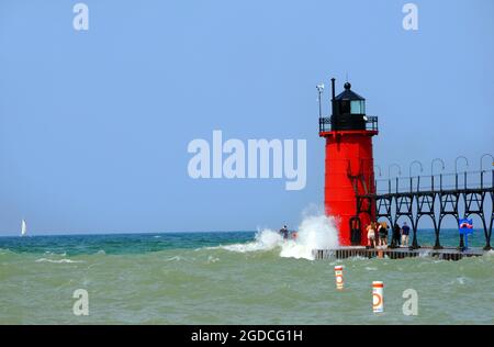 Touristen ignorieren gefährliche Wellen und reisen zum Ende des Piers, um den South Haven Lighthouse am Lake Michigan zu sehen. Beamte wurden gezwungen, den Pier zu schließen Stockfoto