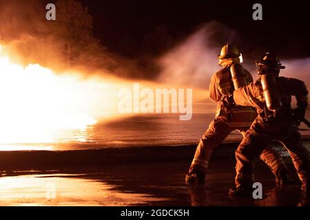 US Marine Corps Aircraft Rescue and Firefighting Specialists with Headquarters and Headquarters Squadron and Marine Wing Support Squadron 271, Conduct live Fuel Fire Burn Training on Marine Corps Air Station Cherry Point, North Carolina, 3. Februar 2021. Die Marineinfanteristen benutzen die Wassertürme auf den P-19 Feuerwehrfahrzeugen, um die Flammen zu kontrollieren, und wenn das Feuer kleiner ist, benutzen sie sogenannte „Handlinenbohrer“, um die Flammen vollständig zu löschen. Handbohrer sind eine Methode zur Brandbekämpfung mit Handschläuchen. Mit Handlinientübungen können die Marineinfanteristen den Wasserdruck von Th besser verstehen Stockfoto