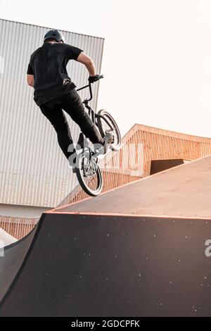 Ein junger Fahrer auf einem BMX-Fahrrad macht Tricks in der Luft. BMX Freestyle in einem Skatepark. Stockfoto