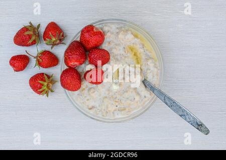 Ein Teller mit Haferbrei und reifen saftigen Erdbeeren auf einem weißen Tisch Stockfoto