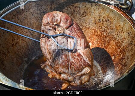 Ein Stück Fleisch wird in kochendem Öl gebraten. Kochen von Pilaf in einem Kessel, ein Schritt-für-Schritt-Rezept für echten Pilaf. Stockfoto