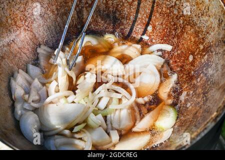 Die gehackte Zwiebel wird in kochendem Öl gebraten. Kochen von Pilaf in einem Kessel, ein Schritt-für-Schritt-Rezept für echten Pilaf. Stockfoto