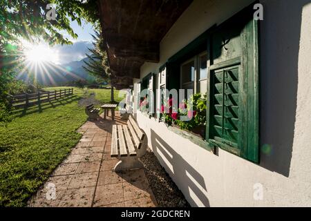 Öffentliches traditionelles österreichisches Alpenhaus, bekannt als das ehemalige Filmset der Serie 'der Bergdoktor' mit typischen Balkonblumen bei Sonnenuntergang in Wil Stockfoto