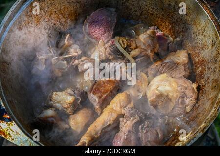 Gehackte Zwiebeln und Fleischstücke werden in kochendem Öl gebraten. Kochen von Pilaf in einem Kessel, ein Schritt-für-Schritt-Rezept für echten Pilaf. Stockfoto