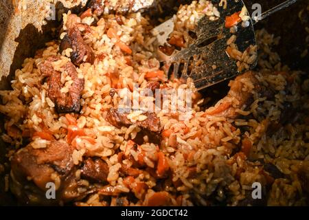 Traditionelles orientalisches Pilaf in einem Kessel an einem sonnigen Tag. Schritt-für-Schritt-Rezept für echten Pilaf. Stockfoto