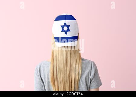 Junge Frau in stilvoller Mütze mit israelischer Flagge auf farbigem Hintergrund Stockfoto