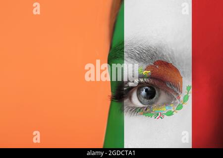 Junge Frau mit Gesicht in Farben der mexikanischen Flagge auf orangefarbenem Hintergrund, Nahaufnahme Stockfoto