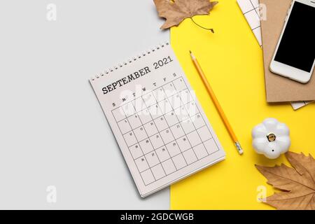 Kalender mit Mobiltelefon, Notizbuch und Herbstblättern auf farbigem Hintergrund Stockfoto